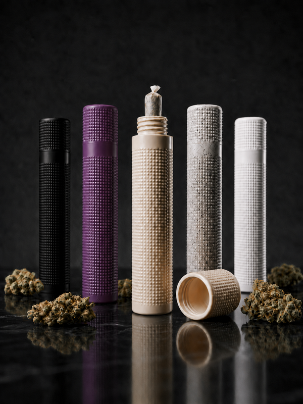 Fünf geruchshemmende Premium Joint Tubes von Strainlab in den Farben Schwarz, Lila, Beige, Grau gesprenkelt und Weiß. Die Hüllen stehen auf einer dunklen Oberfläche umgeben von Cannabis-Blüten. In der geöffneten, beigen Tube in der Mitte steckt ein fertig gerollter Joint.